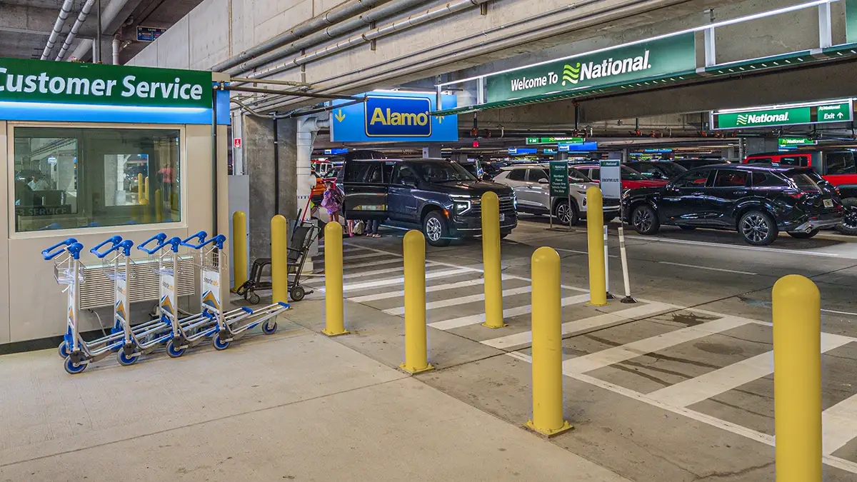 Alamo and National car rental customer service counter and vehicle return lanes inside an airport garage.