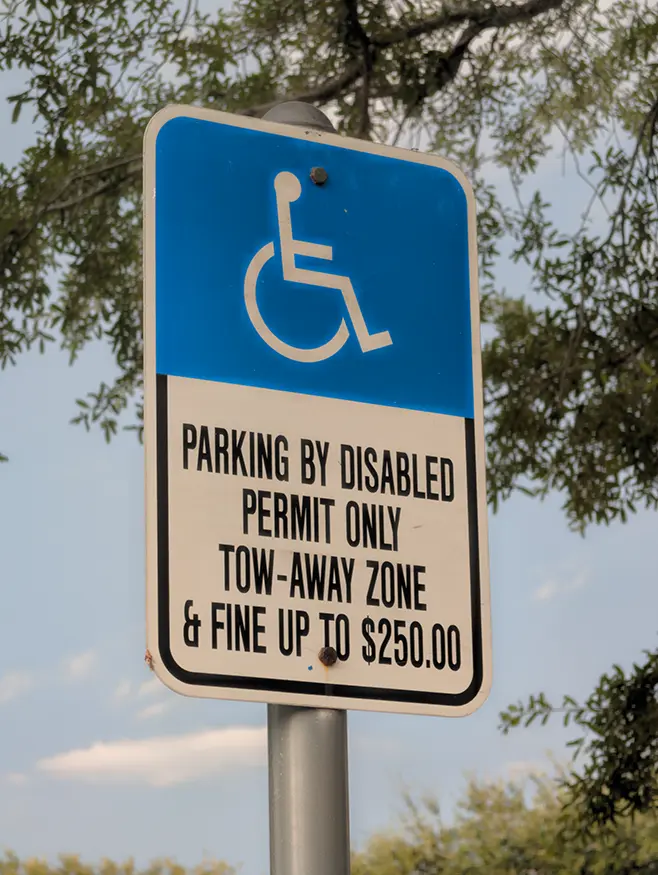 Florida disabled parking violation sign showing $250 penalty under F.S. 318.18 Close-up of a Florida blue disabled parking sign with wheelchair symbol and white text reading "PARKING BY DISABLED PERMIT ONLY" and "250 DOLLAR FINE F.S. 318.18"