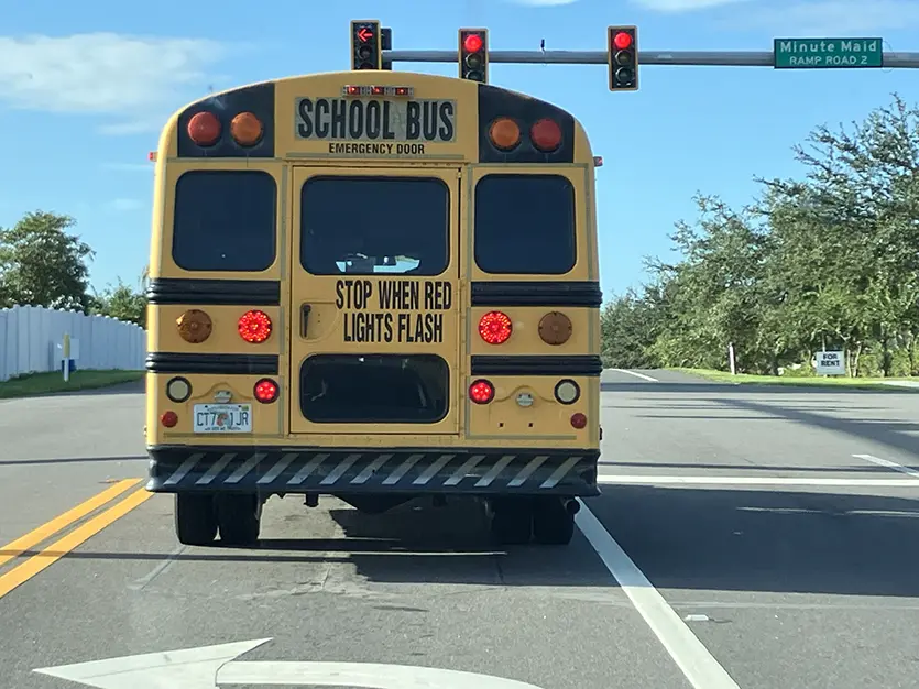 Florida school bus stopped at a road junction Yellow Florida school bus stopped at a red light displaying text reading Stop When Red Lights Flash.