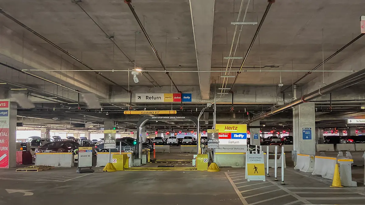 Hertz, Dollar, and Thrifty car rental return lane entrance inside a Florida airport garage.